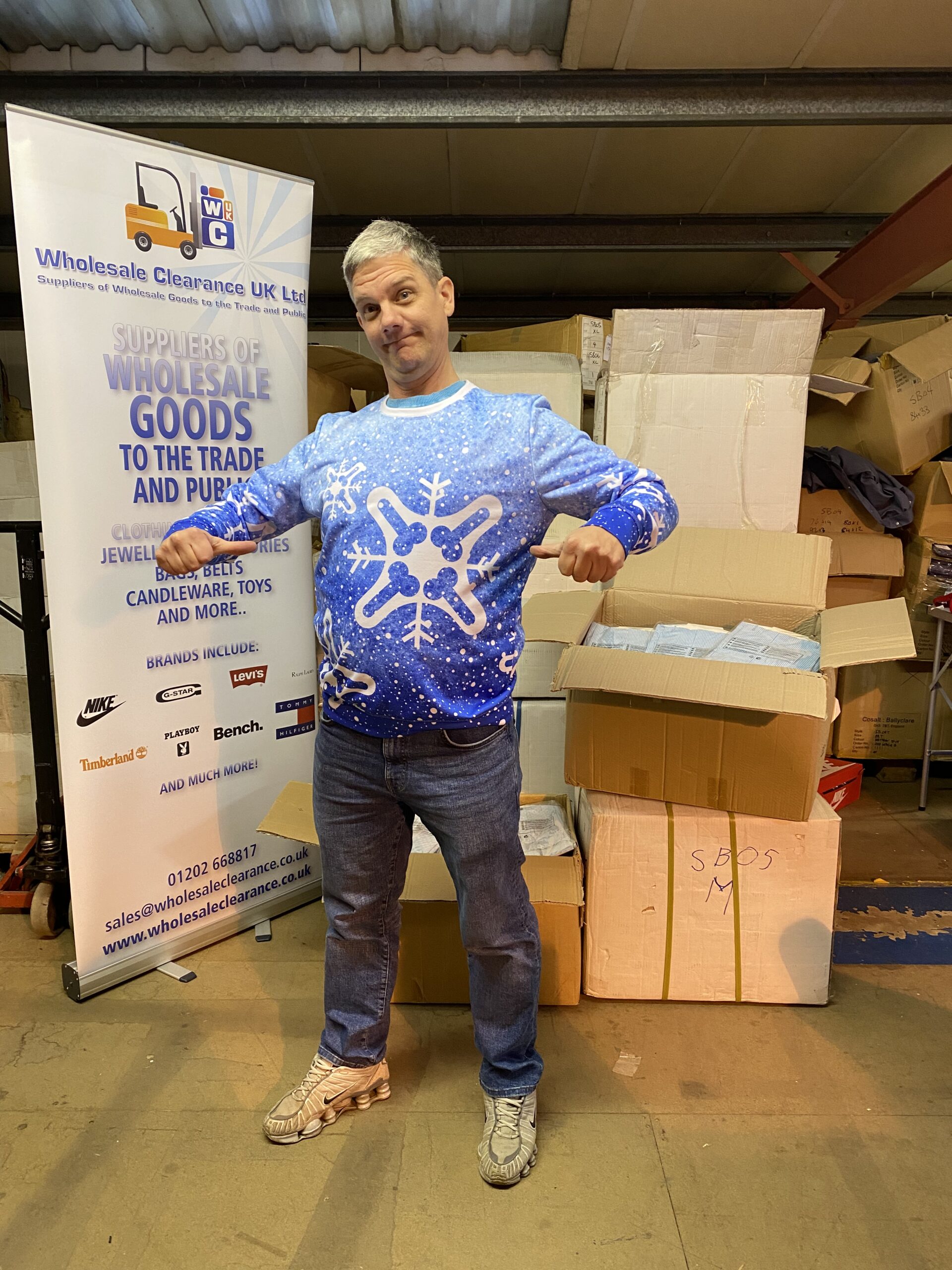 Karl Baxter modelling a novelty Christmas jumper beside the Wholesale Clearance UK banner